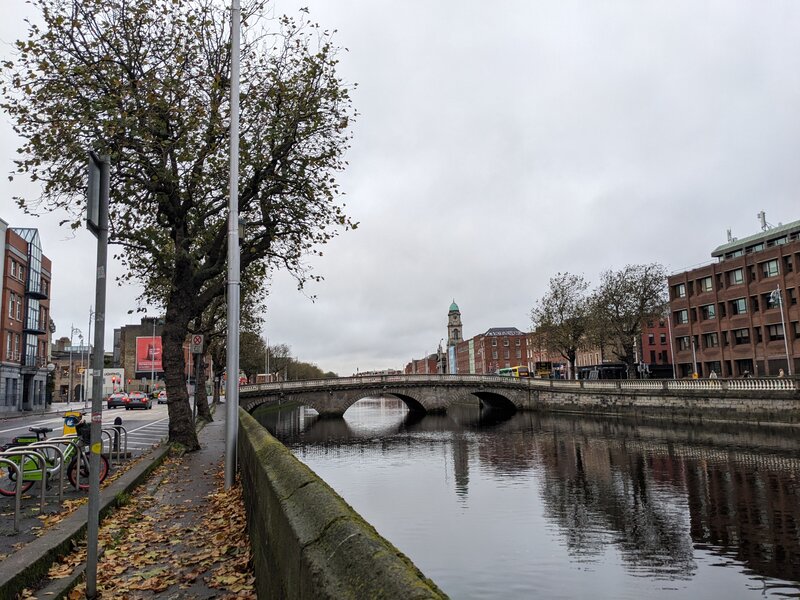 A river with an overcast sky, next to an empty street