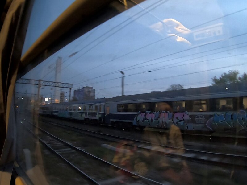 A train window showing the tracks and a reflection of the cabin