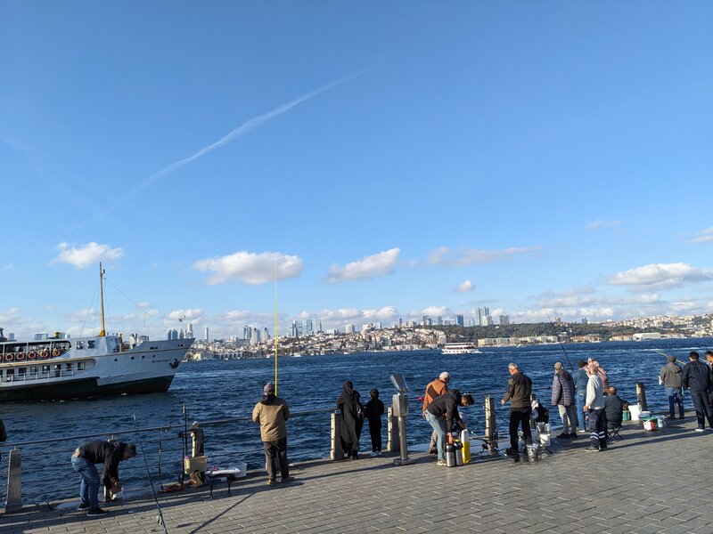 People fishing on a strait with a clear view of the other side