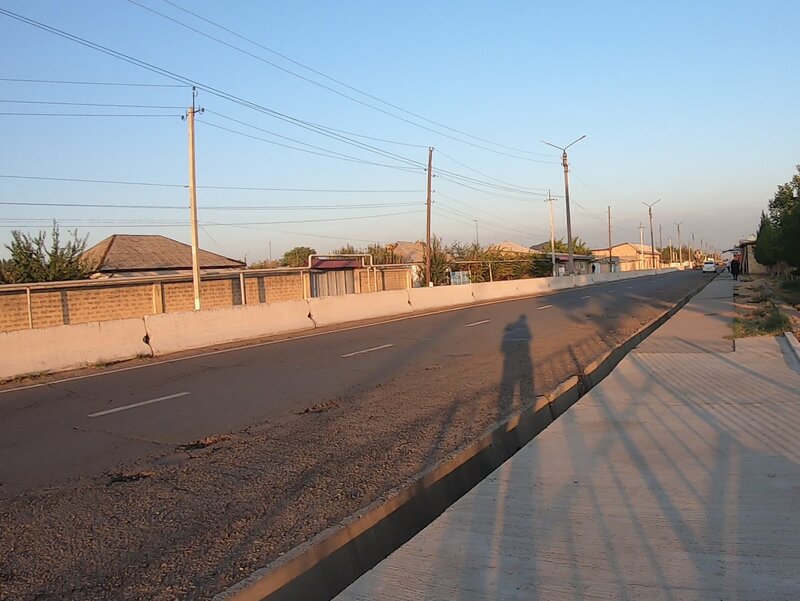 A long shadow cast against the sunset onto an empty street