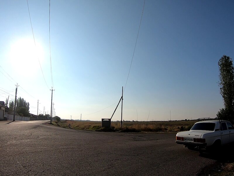A white Zhiguli driving past an empty field