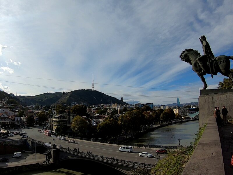 A statue of horse-riding man overlooking a river